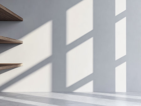 Wooden shelves are positioned against a light wall, with long shadows stretching across the surface. The scene captures a blend of light and shadow, creating a calm atmosphere.の素材