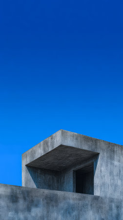 A minimalistic concrete structure is set against a vibrant blue sky. The geometric lines and angles create a bold statement of modern architecture and simplicity.の素材