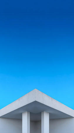 A minimalist building with a sharply angled roof stands against a bright blue sky. The scene captures the simplicity of modern architecture during the day, highlighting clean lines and openness.の素材