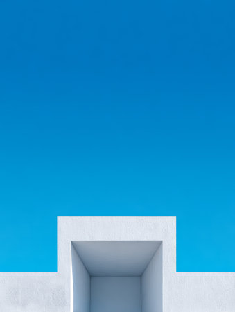 A simple white structure features a rectangular opening, surrounded by a clear blue sky. This outdoor scene evokes a sense of openness and tranquility during daytime.の素材