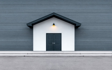 A sleek entrance features a small house-like structure against a gray wall, illuminated by a warm light. The area is empty, showcasing a modern aesthetic at dusk.の素材