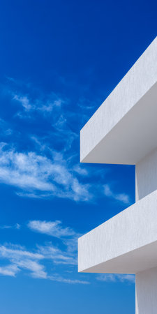A modern building features sharp white lines against a brilliant blue sky filled with fluffy clouds. The scene captures a serene atmosphere typical of a coastal location.の素材