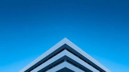 The building displays a contemporary design with sharp angles and layered structure, set against a bright, cloudless sky, showcasing modern urban architecture.の素材