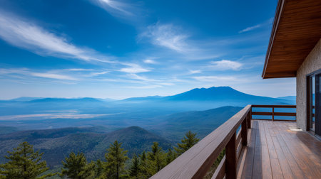 A wooden balcony offers a stunning view of mountains and valleys under a bright blue sky. The landscape shows lush greenery and rolling hills in the distance.の素材