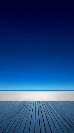 Wide view of a calm beach with smooth sand and clear blue water under a bright sky. The horizon blends seamlessly into the light, creating a tranquil atmosphere.の素材