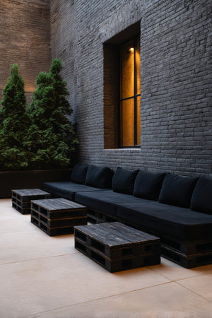This outdoor lounge features black pallet sofas and tables, complemented by lush greenery. The space is designed for relaxation in a modern urban environment.の素材