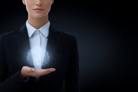 A business professional stands confidently in a suit, holding a glowing brain in her hand. The dark background enhances the focus on the symbol of creativity and intelligence.の素材