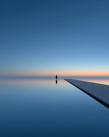 A person stands quietly at the edge of a smooth water surface, surrounded by a tranquil atmosphere as the sky transitions to morning light. This moment captures solitude and peace.の素材