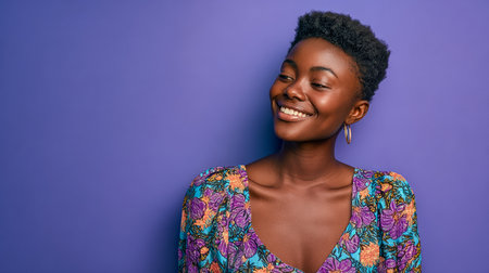 A woman with a radiant smile poses confidently against a bold purple backdrop. Her colorful floral dress and bright expression convey happiness and warmth.の素材