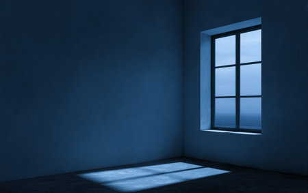 A quiet room features blue walls and a single window. Soft light casts shadows across the floor as night falls outside, creating a serene atmosphere.の素材