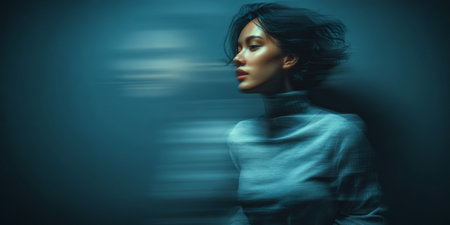A young woman dressed in a gray top is captured with motion blur, creating a dynamic effect. The background fades into soft colors, emphasizing her graceful movement.の素材