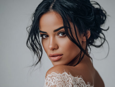 A young woman poses gracefully in a delicate bridal gown with lace accents, showcasing her natural beauty and elegance under soft lighting.の素材