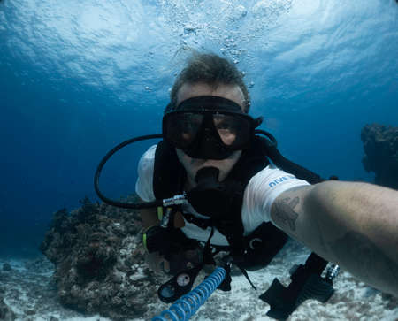 young dive instructor taking a selfie in the caribbean oceanの写真素材