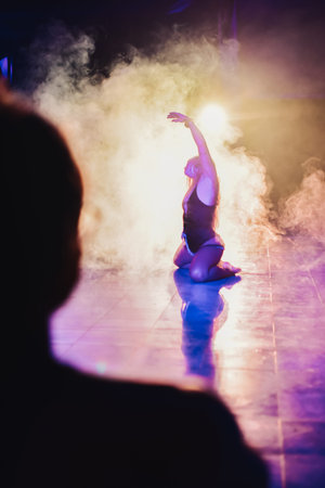 silhouette of a woman dancing between lights and smoke