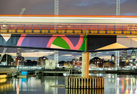 Train passing fast by bridge over lake in townの写真素材
