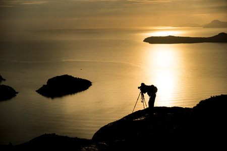 Photographer photographing the sunrise at seaの写真素材