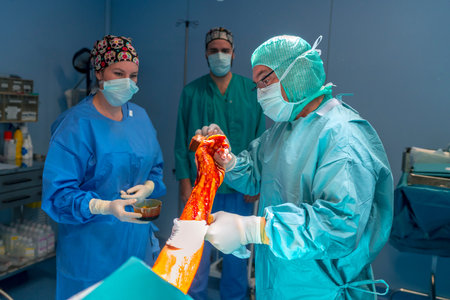 Surgeon painting the area to be operated on. The operating room assistant holds the bucket while the...