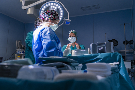 Surgeon waiting to start the operation. She has the table with all the surgical material ready. The rest of the assistants are waiting for your instructions.の写真素材