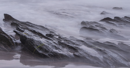Evaporated water covers rocks on the beachの写真素材