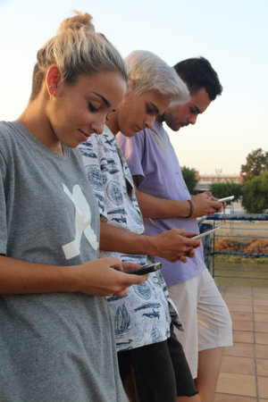 A blonde girl, a boy of gray hair and black-haired boy, writing three at a time on Their smartphones