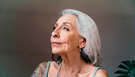Offbeat close-up portrait of an elderly woman of unusual style. Elderly female person with colored personality. Tattooed senior citizen. Confident beautiful old woman.の素材