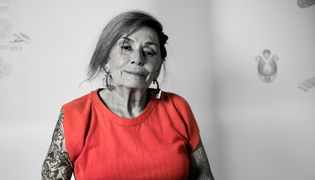 Offbeat close-up portrait of an elderly woman of unusual style. Elderly female person with colored personality. Tattooed senior citizen. Confident beautiful old woman.の素材