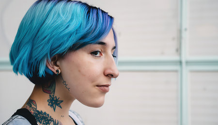 Close-up portrait of a tattooed girl with blue dyed hairの素材