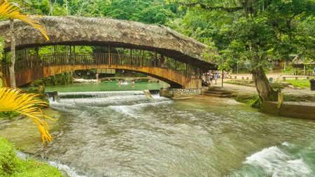 river passing under a rustic bridge in the jungleの写真素材