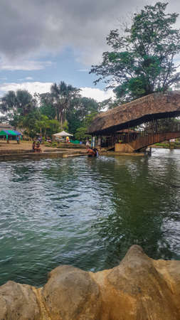 river passing under a rustic bridge in the jungleの写真素材