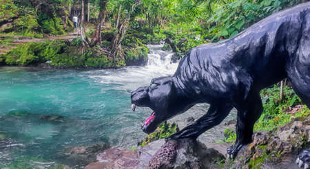 animal statue standing next to a stream in the jungleの写真素材