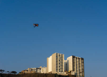 kite flying over buildings in the empty and blue skyの写真素材