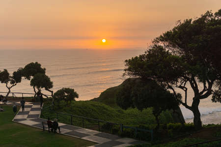 Sunset Landscape in the shore of Lima Peru, view from a park with grass and a treeの写真素材