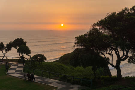 Sunset Landscape in the shore of Lima Peru, view from a park with grass and a treeの写真素材