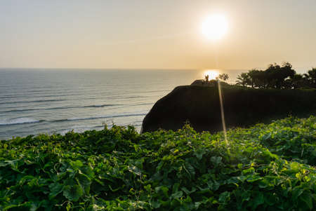 Sunset Landscape in the shore of Lima Peru, view from a park with grass and a treeの写真素材
