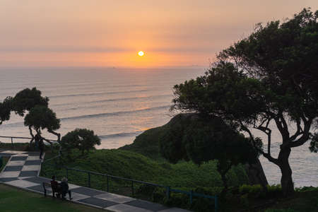 Sunset Landscape in the shore of Lima Peru, view from a park with grass and a treeの写真素材