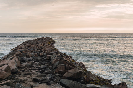 blue ocean panorama of Lima coast, sun reflection and calm waves, pile of rocks in the sea, rock pathの写真素材