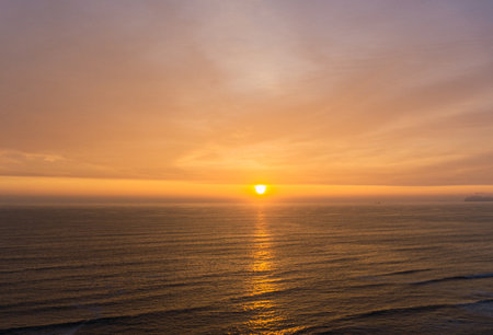 Beautiful sunset in Lima Peru, bright sky and underexposed beach, golden hour, orange skyの写真素材