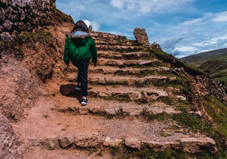 unrecognizable woman in green coat climbing rustic stairs in San Pedro de Cajas Tarma Peruの写真素材
