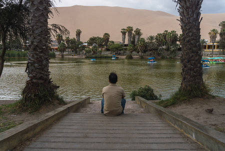 Young men appreciating the Huacachina lagoon in Ica Peruの写真素材