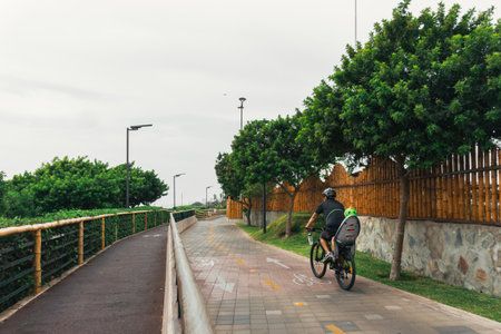 Unrecognizable adult man and kid riding a bike in Miraflores district, Lima Peruの写真素材