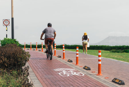 Unrecognizable person riding a bike and girl walking in Miraflores district, Lima Peru