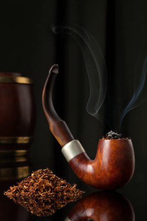 Lt Wooden Elegant Brown Tobacco pipe with tobacco and tobacco wooden containers in dark background....