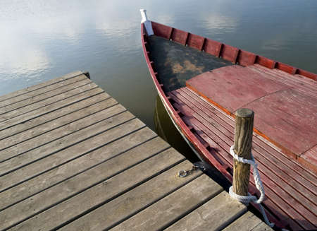 Old red fishing boat tied to a wooden pierの写真素材
