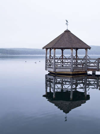 Wooden Gazebo located on the calm waters of a lakeの写真素材