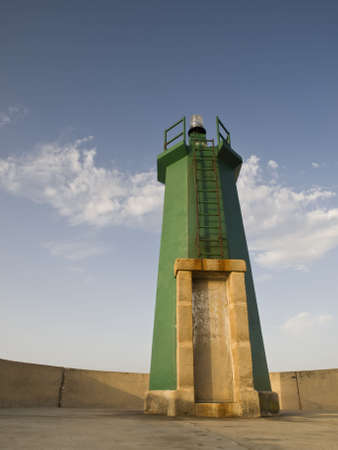 Green lighthouse seen from the bottom, with a nice blue skyの写真素材