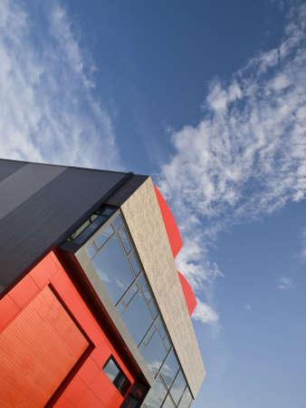 Red modern factory building and blue sky with clouds. Vertical Composition.の写真素材