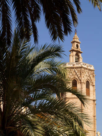 The bell tower of the cathedral of Valencia is called El Miguelete, and here you can see it in a vertical composition behind some palm treesの写真素材