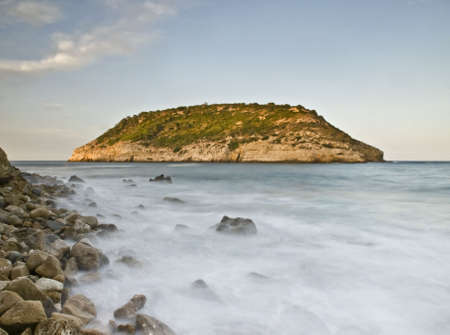 Island seen from the coast at sunset. Long time of exposure used to give a silky effect to the waterの写真素材