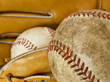 Composition showing the typical elements of the game of baseball: a ball used in the foreground and another ball on a glove in the background. Focus on the foregroundの写真素材