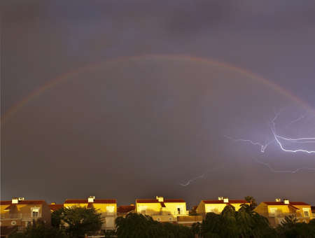 Lightning inside the arc of a rainbowの写真素材
